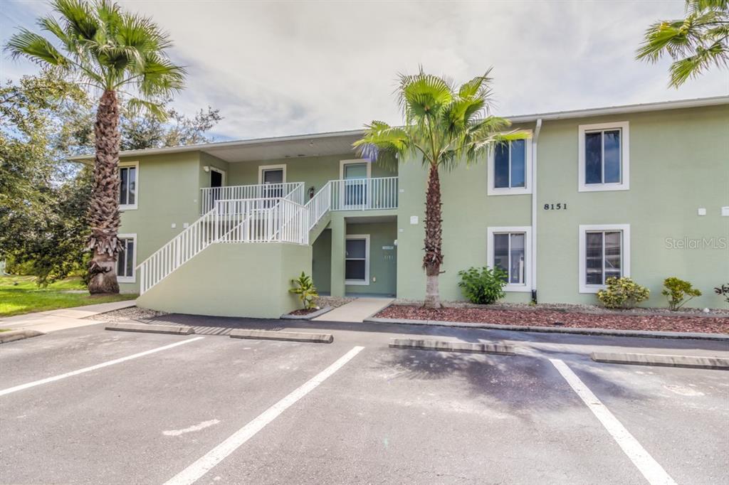 A two-story light green apartment building with palm trees and a parking lot in front — 8151 MEMORY LANE UNIT 118, ROTONDA WEST, FL