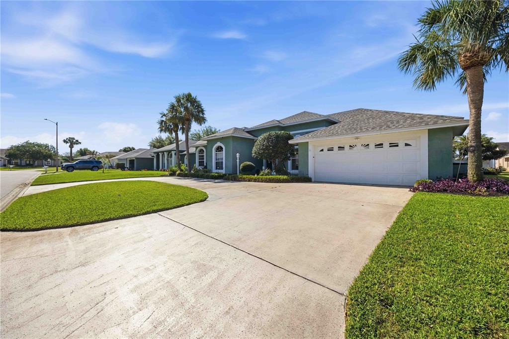 A single-story house with a white garage door, green stucco exterior, and a concrete driveway — 355 RUBY LAKE LOOP, WINTER HAVEN, FL