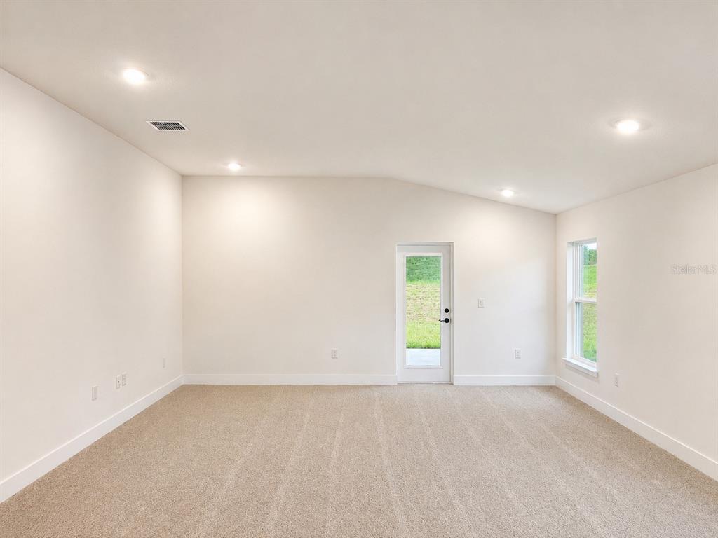 An empty room with beige carpet, white walls, recessed lighting, a glass door, and a window — 255 VERNY GROVE LANE, LEESBURG, FL