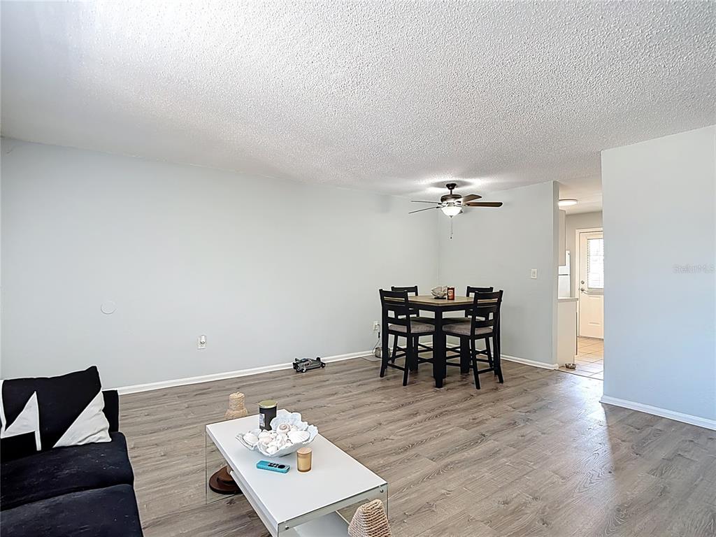 A living and dining area with light gray walls, wood-look flooring, and a ceiling fan — 201 PINE VIOLET COURT UNIT 201, TAMPA, FL