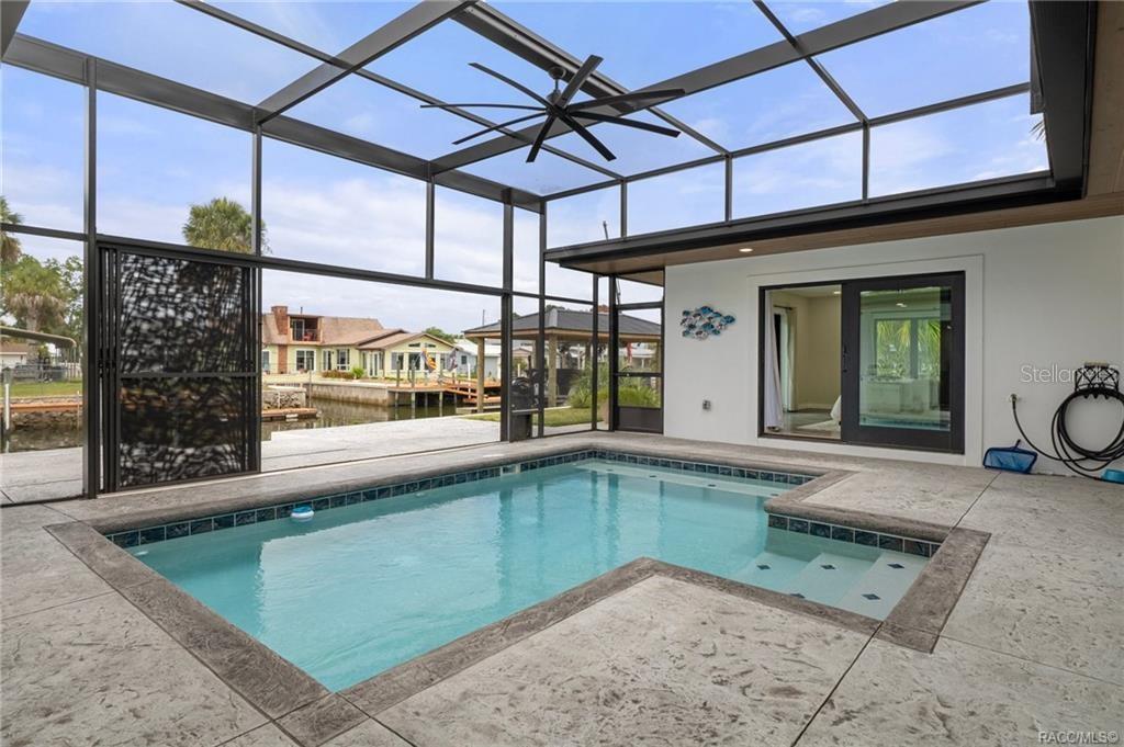 A screened-in pool patio features a concrete deck, a ceiling fan, and a canal view — 1941 NW 17TH STREET, CRYSTAL RIVER, FL