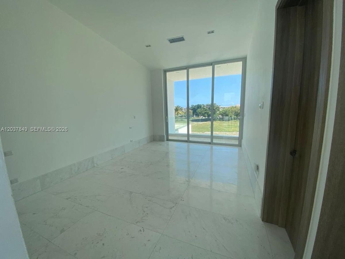 An empty room features white walls, marble flooring, and a large sliding glass door — 0 las palmitas, FL