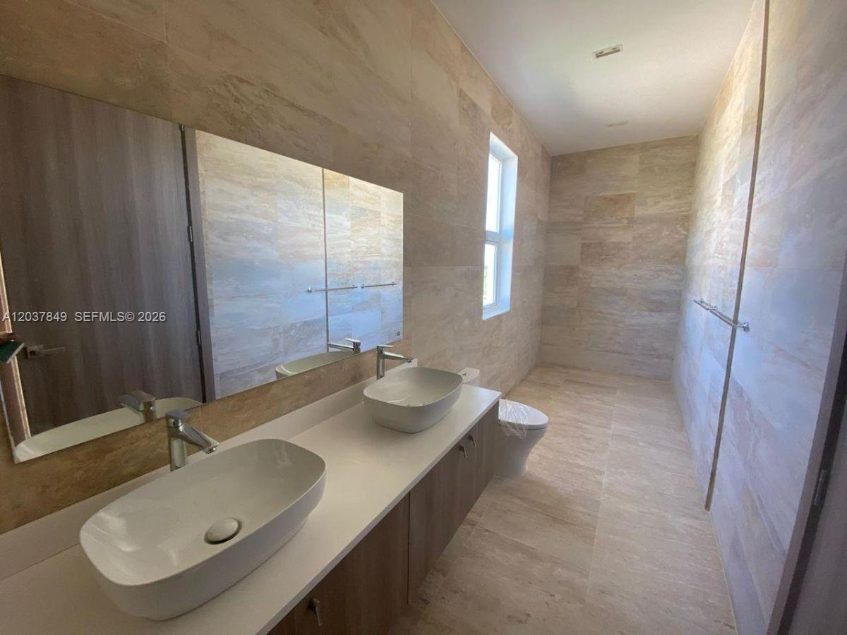 A modern bathroom features a double vanity with vessel sinks, a large mirror, and tiled walls — 0 las palmitas, FL