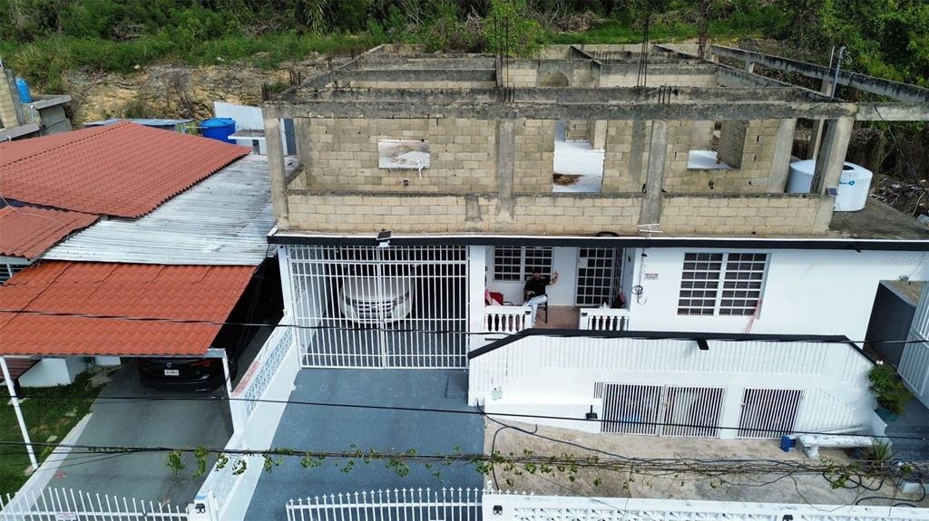 An aerial view shows a two-story house with a partially constructed concrete upper level — 26 BO FACTOR 1 PARCELAS ANIMAS #399 CALLE 26, ARECIBO, PR