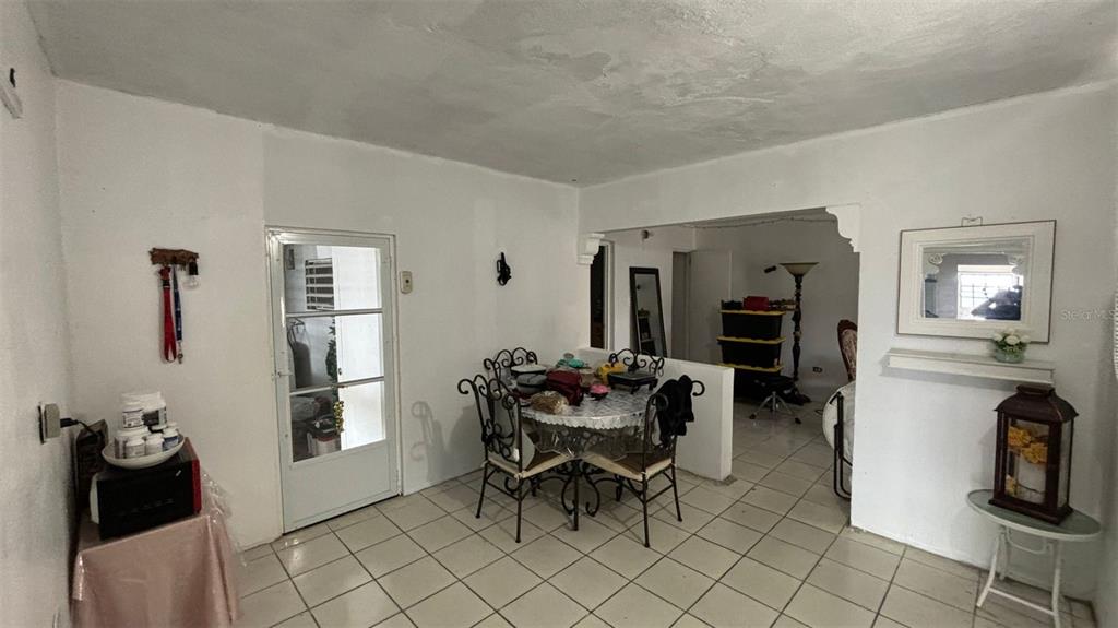 A dining area with a round table, tiled floors, and a doorway leading outside — 26 BO FACTOR 1 PARCELAS ANIMAS #399 CALLE 26, ARECIBO, PR