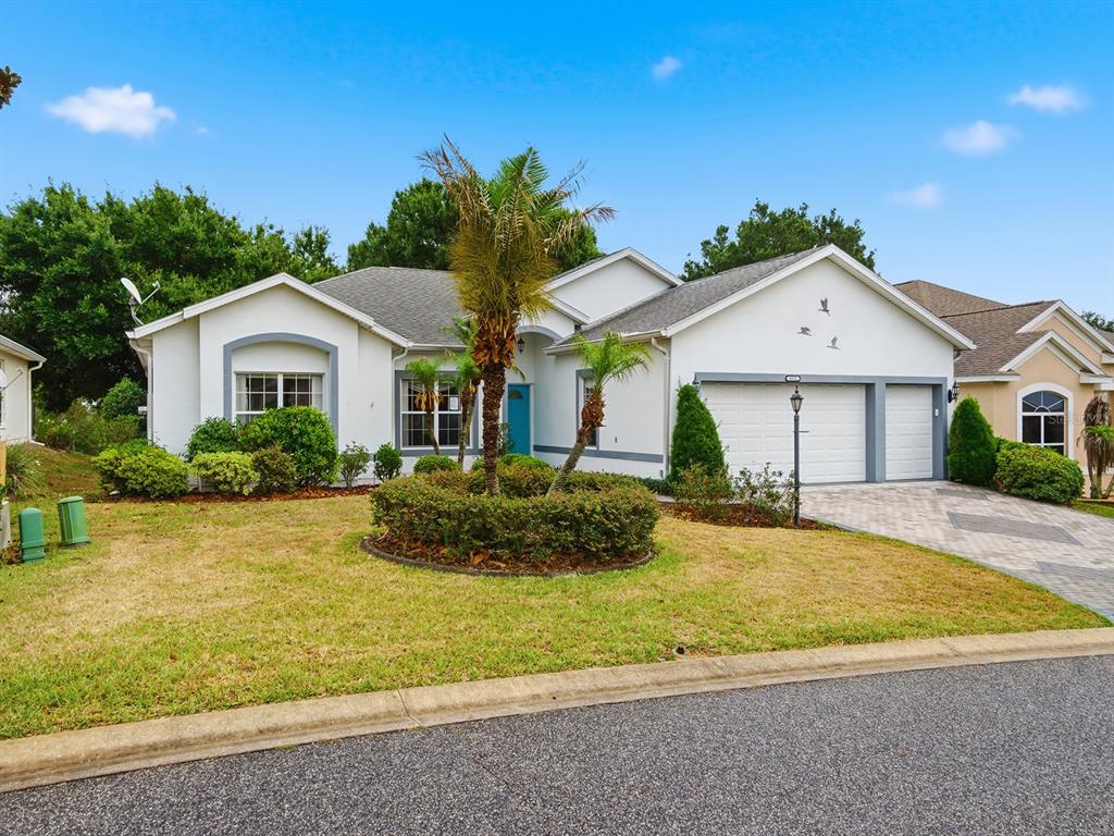 A single-story house with a white stucco exterior, a two-car garage, and a palm tree — 4835 SABLE RIDGE COURT, LEESBURG, FL