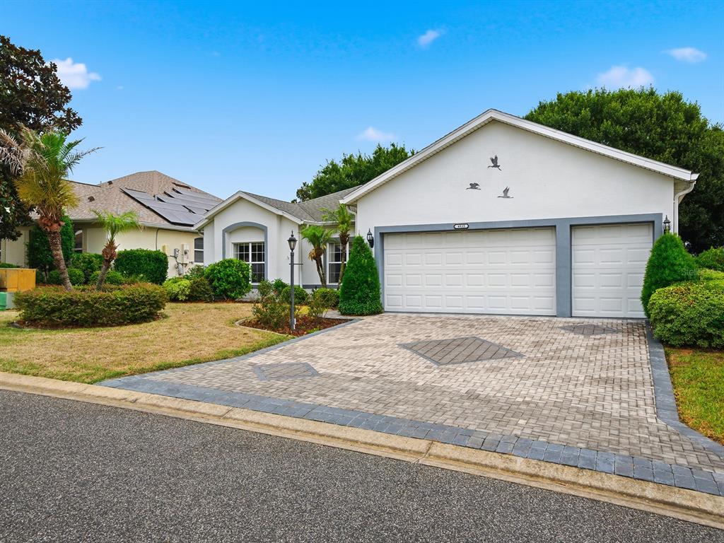 A single-story house with a paved driveway, a three-car garage, and a landscaped front yard — 4835 SABLE RIDGE COURT, LEESBURG, FL