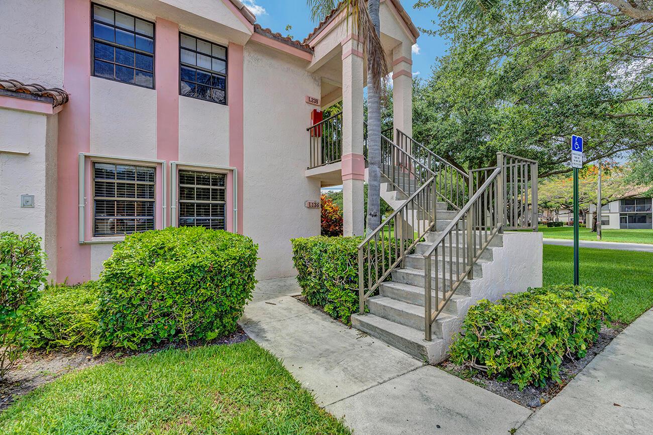 An exterior view of a two-story apartment building with stairs leading to an upper unit — 3191 Leewood Terrace # L138, Boca Raton FL 33431, BOCA RATON, FL