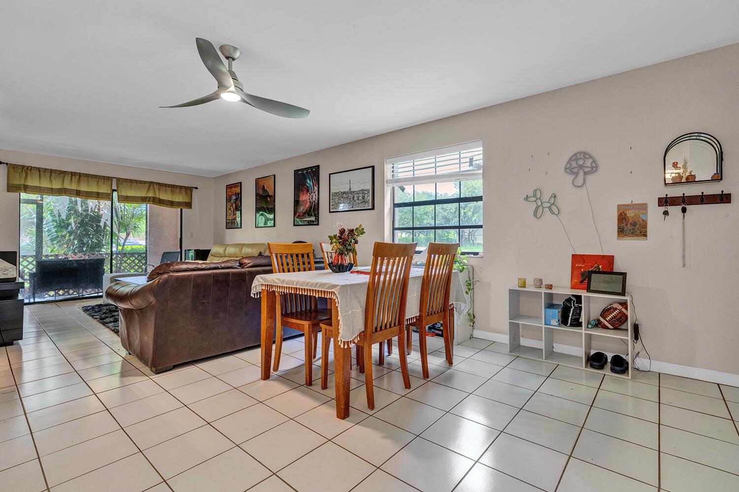 A dining area with a wooden table and chairs sits next to a living room — 3191 Leewood Terrace # L138, Boca Raton FL 33431, BOCA RATON, FL