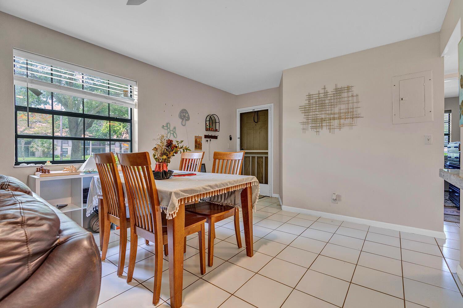 A dining area features a wooden table, four chairs, tiled floors, and a large window — 3191 Leewood Terrace # L138, Boca Raton FL 33431, BOCA RATON, FL