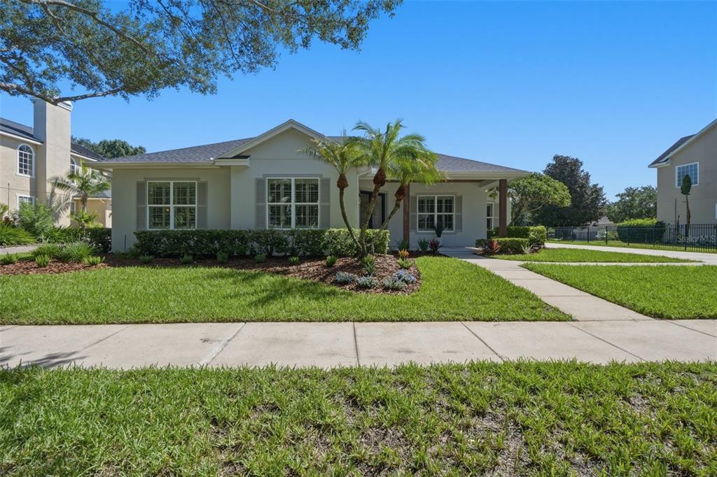 A single-story house with a light-colored exterior, a front porch, and a landscaped yard — 9589 PINE LILY STREET, ORLANDO, FL