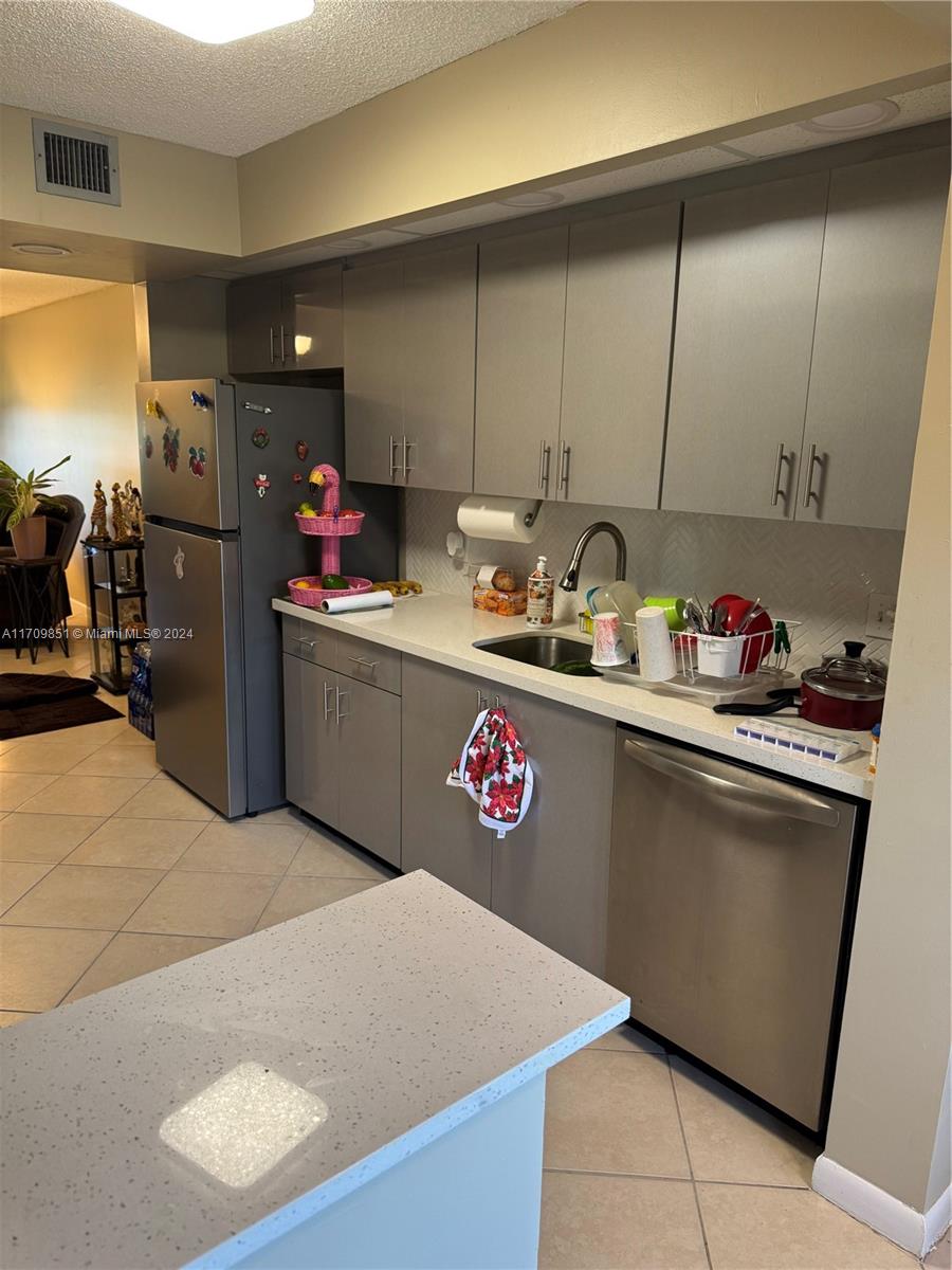 A kitchen features gray cabinets, stainless steel appliances, and a white countertop with a sink — 12650 SW 6th St # 411K, Pembroke Pines FL 33027, PEMBROKE PINES, FL