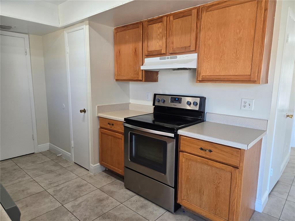 A kitchen features oak cabinets, a stainless steel stove, and light-colored countertops — 271 LA PAZ DRIVE, KISSIMMEE, FL