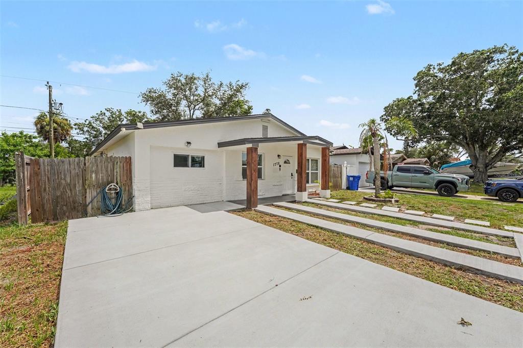 A single-story house with a white exterior, wooden porch posts, and a concrete driveway — 1778 NEW HAMPSHIRE AVENUE NE, ST PETERSBURG, FL