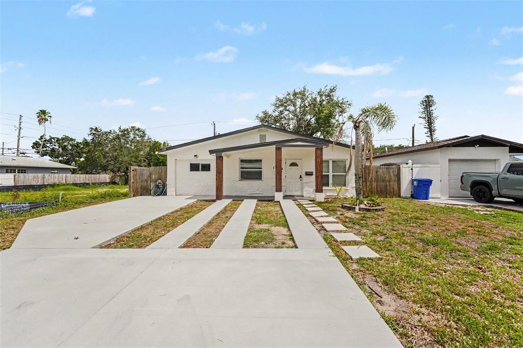 A single-story house with a concrete driveway, a covered porch, and a detached garage — 1778 NEW HAMPSHIRE AVENUE NE, ST PETERSBURG, FL