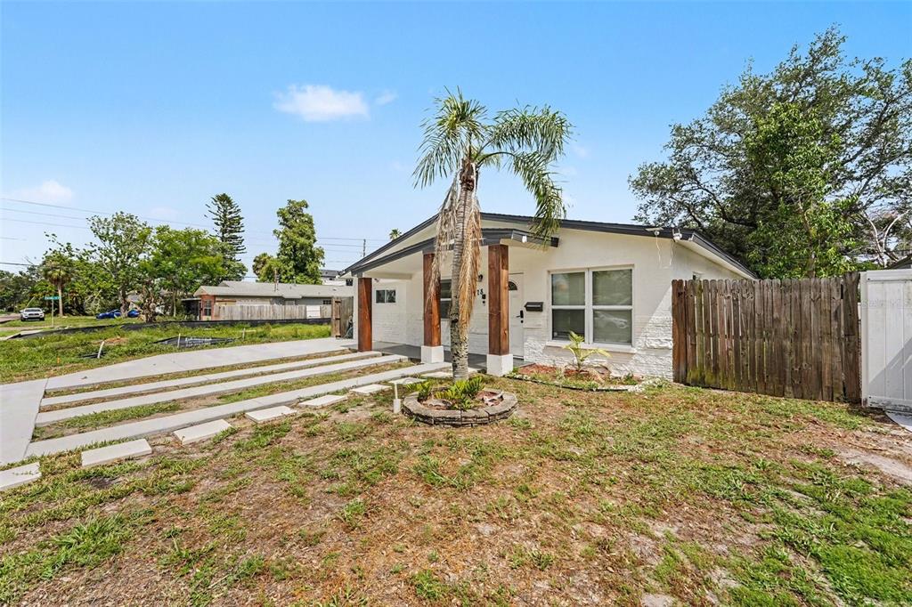A single-story white house with a palm tree and a concrete driveway in the front yard — 1778 NEW HAMPSHIRE AVENUE NE, ST PETERSBURG, FL