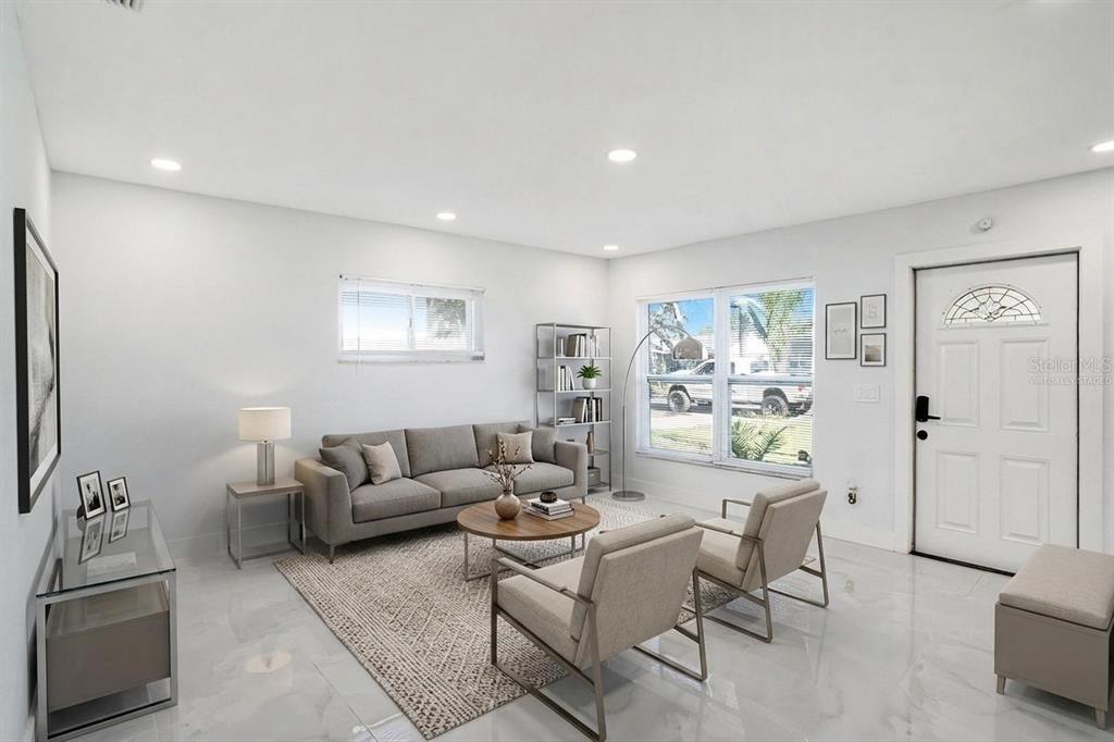 A living room with light tile floors, a gray sofa, two armchairs, and a rug — 1778 NEW HAMPSHIRE AVENUE NE, ST PETERSBURG, FL