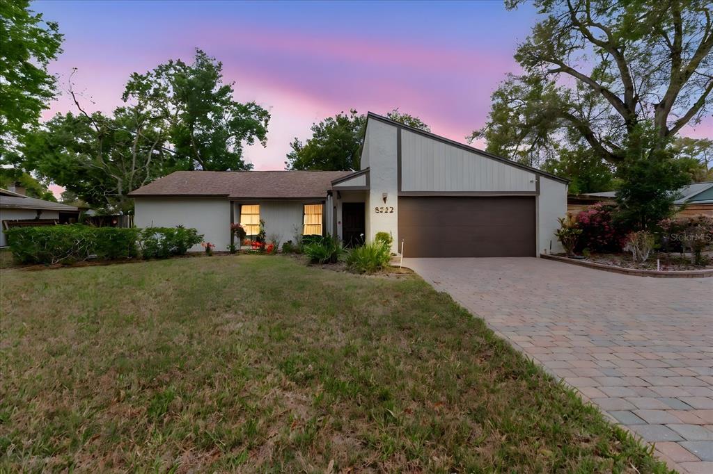 A single-story house with a brown garage door and a paved driveway at dusk — 8222 LA SERENA DRIVE, TAMPA, FL