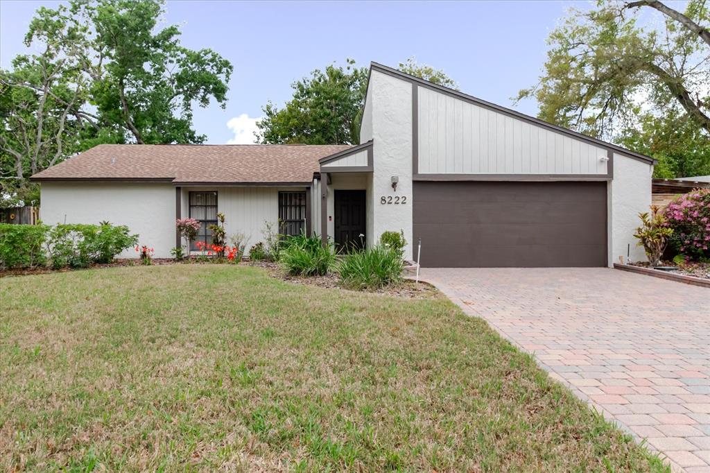 A single-story house with a brown shingle roof, stucco siding, and a paved driveway — 8222 LA SERENA DRIVE, TAMPA, FL