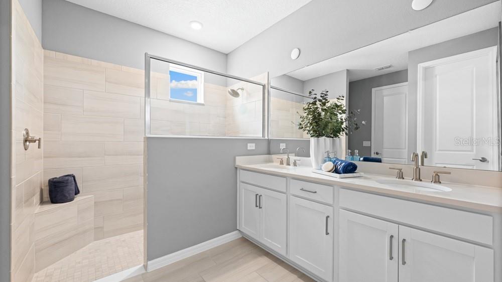 A modern bathroom features a walk-in tiled shower, double vanity, and a large wall mirror — 3512 LUMBER FALLS DRIVE, PLANT CITY, FL