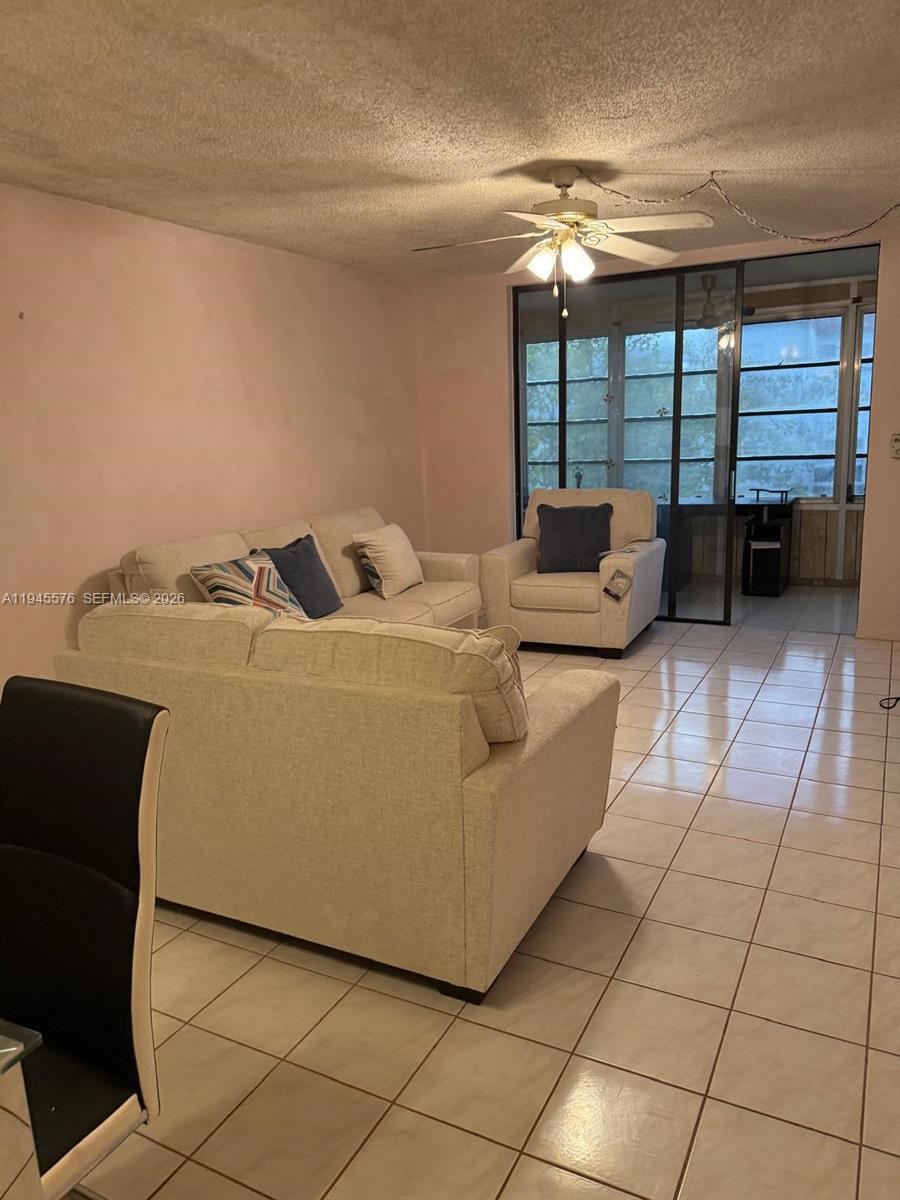 A living room features light-colored sofas, tile flooring, and a sliding glass door — 2850 Somerset Dr # 309L, Lauderdale Lakes FL 33311, LAUDERDALE LAKES, FL