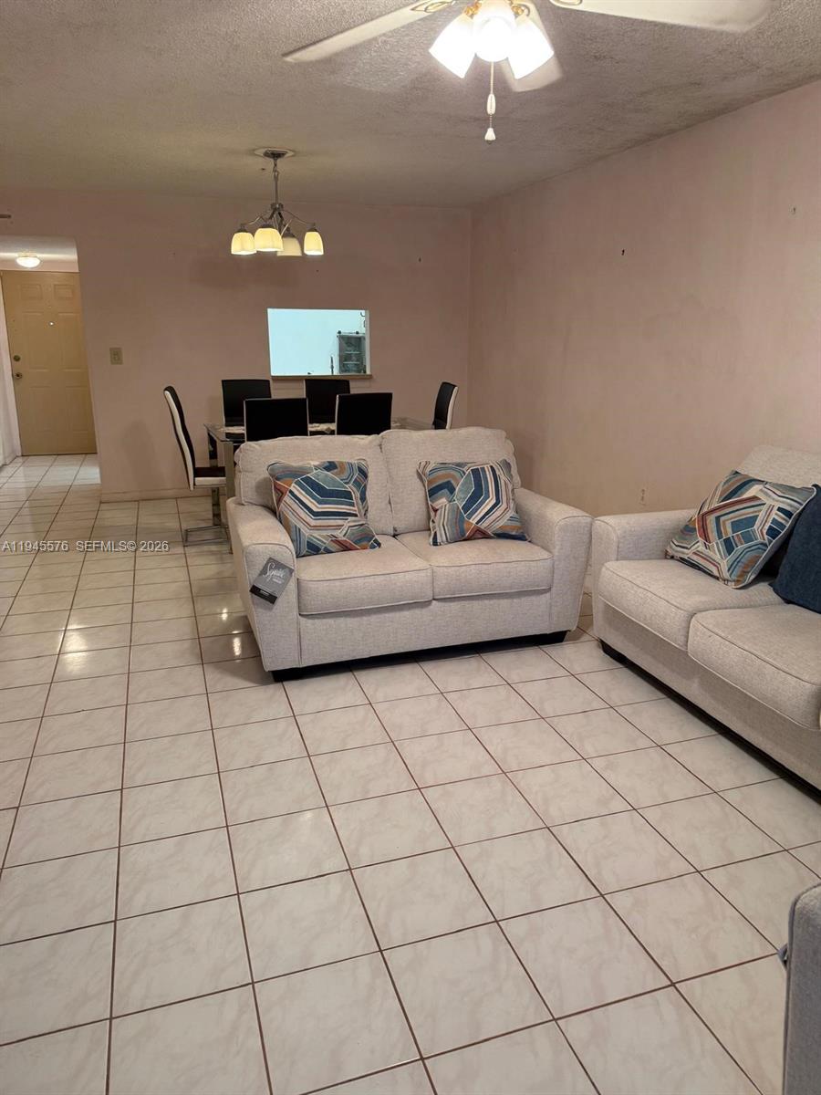 A living room with light-colored tile flooring features two sofas and a dining area — 2850 Somerset Dr # 309L, Lauderdale Lakes FL 33311, LAUDERDALE LAKES, FL