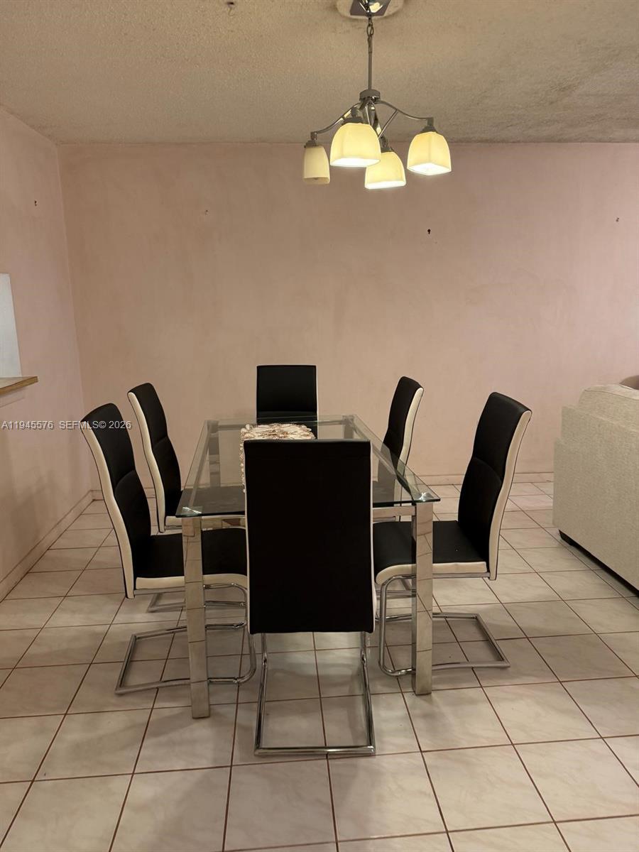 A dining room features a glass-topped table with six black chairs and a pendant light — 2850 Somerset Dr # 309L, Lauderdale Lakes FL 33311, LAUDERDALE LAKES, FL