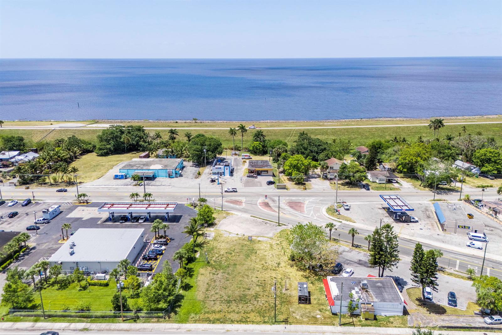 An aerial view shows a coastal commercial area with buildings, parking lots, and a large body of water — 700 Larrimore Road, Pahokee FL 33476, PAHOKEE, FL