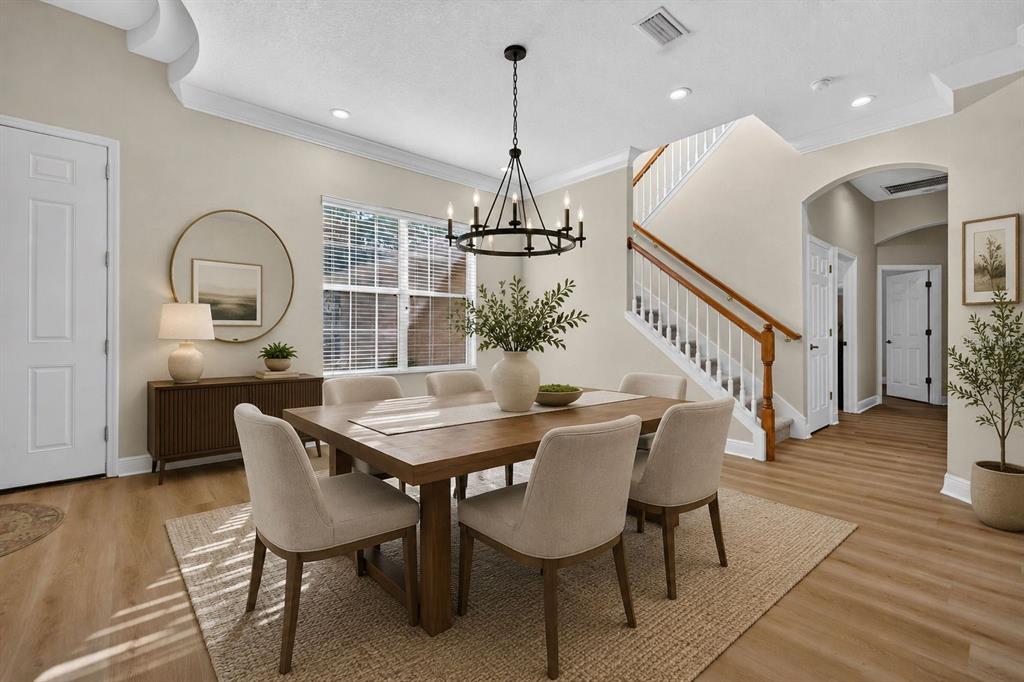A dining room features a wooden table, upholstered chairs, a chandelier, and a staircase — 5112 ABISHER WOOD LANE, BRANDON, FL
