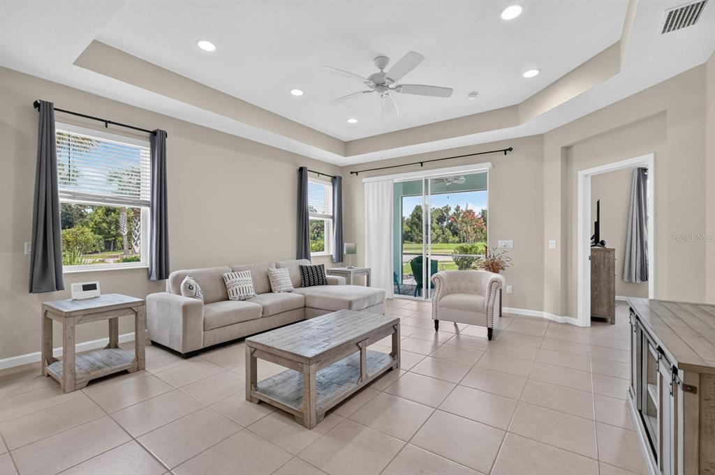 A living room with a sectional sofa, coffee table, tile floors, and sliding glass doors — 497 LOST SHAKER WAY, DAYTONA BEACH, FL