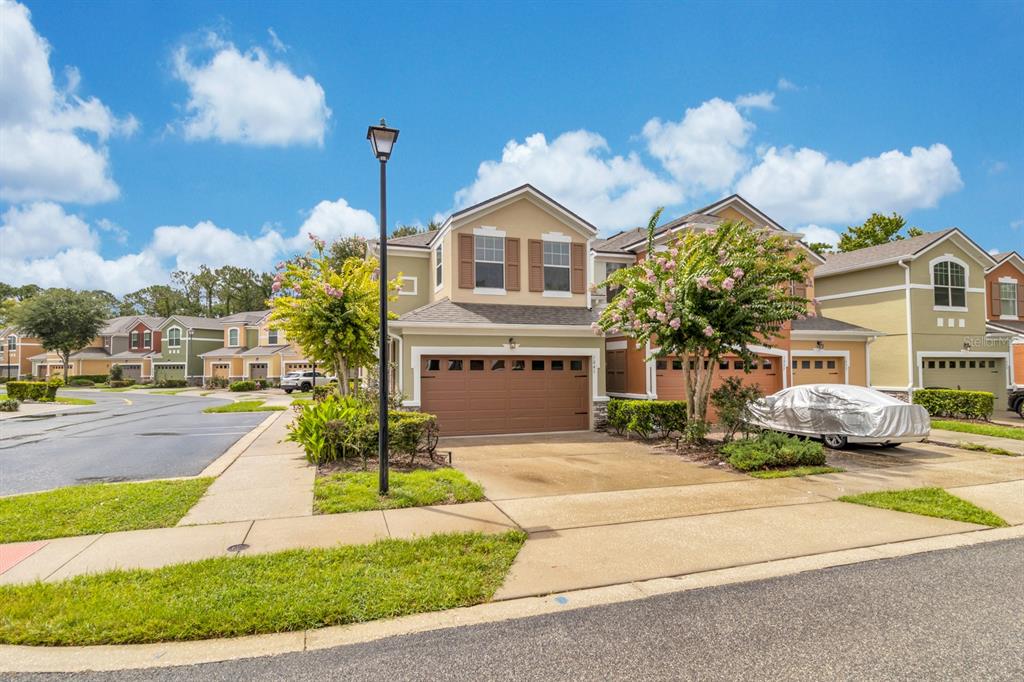 A two-story townhouse with a brown garage door and a covered car parked outside — 1041 LAUREL RIDGE LANE, SANFORD, FL