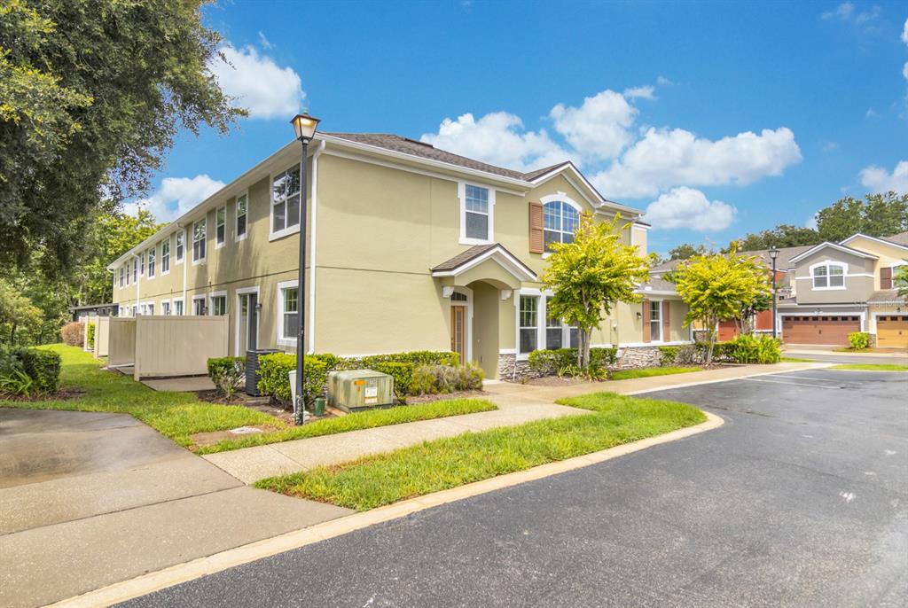 A two-story tan townhouse with a front entrance, stone accents, and a paved parking area — 1041 LAUREL RIDGE LANE, SANFORD, FL