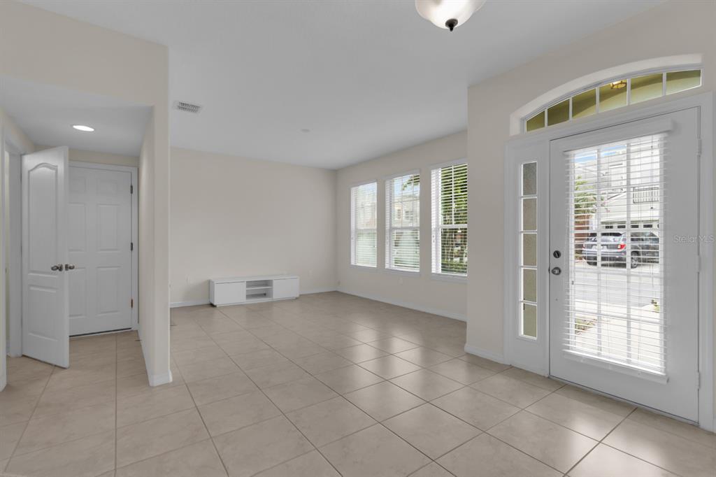 An empty room with beige tile flooring, white walls, and a glass-paneled front door — 1041 LAUREL RIDGE LANE, SANFORD, FL