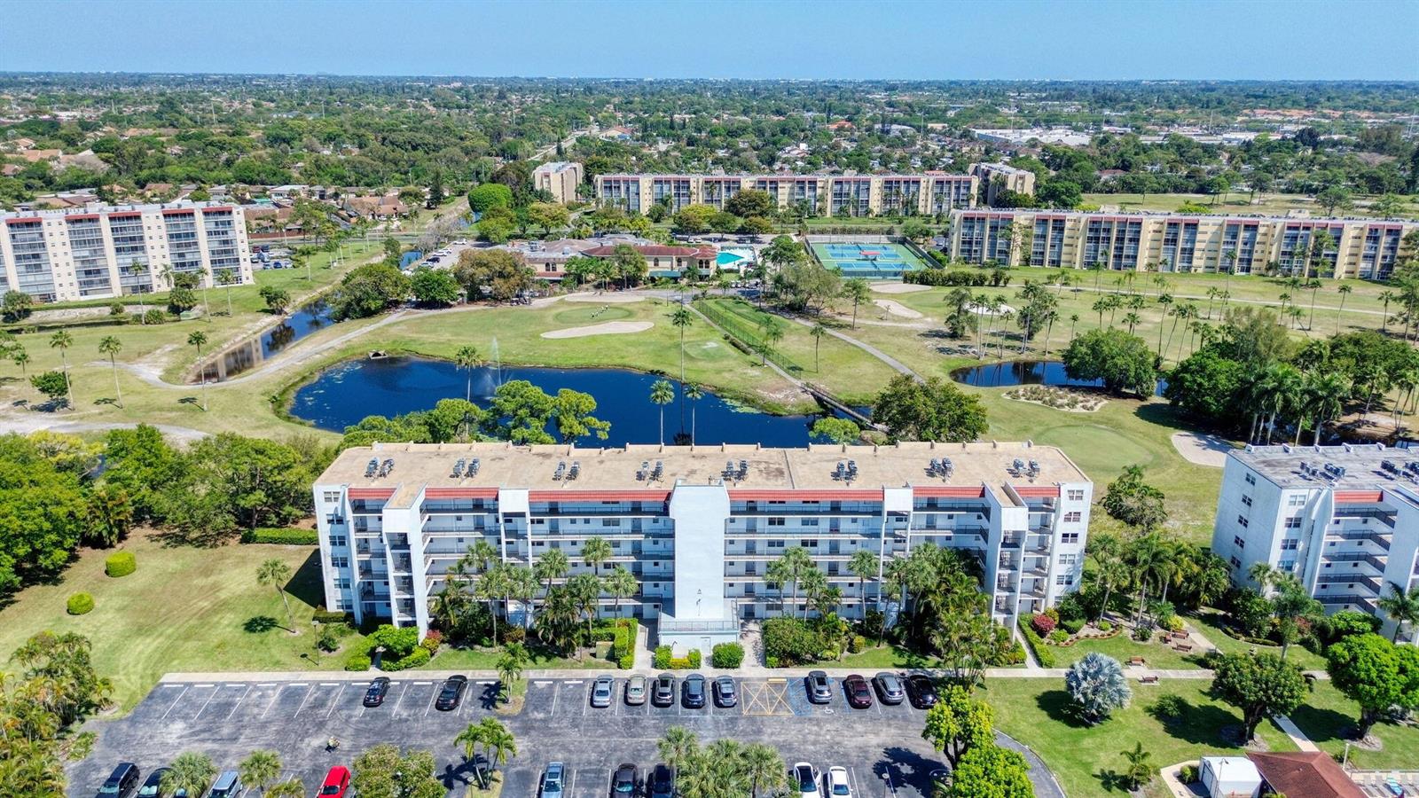 An aerial view shows a multi-story apartment building overlooking a golf course and pond — 3593 Birdie Drive # 203, Lake Worth FL 33467, LAKE WORTH, FL