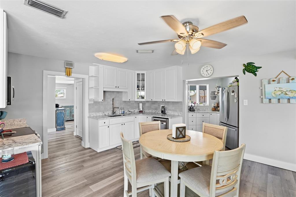 A kitchen and dining area feature white cabinets, granite countertops, and a round wooden table — 300 DELIDO COURT, PUNTA GORDA, FL