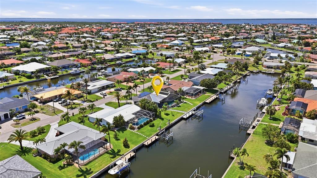 An aerial view shows a waterfront house with a pool and dock in a neighborhood — 300 DELIDO COURT, PUNTA GORDA, FL
