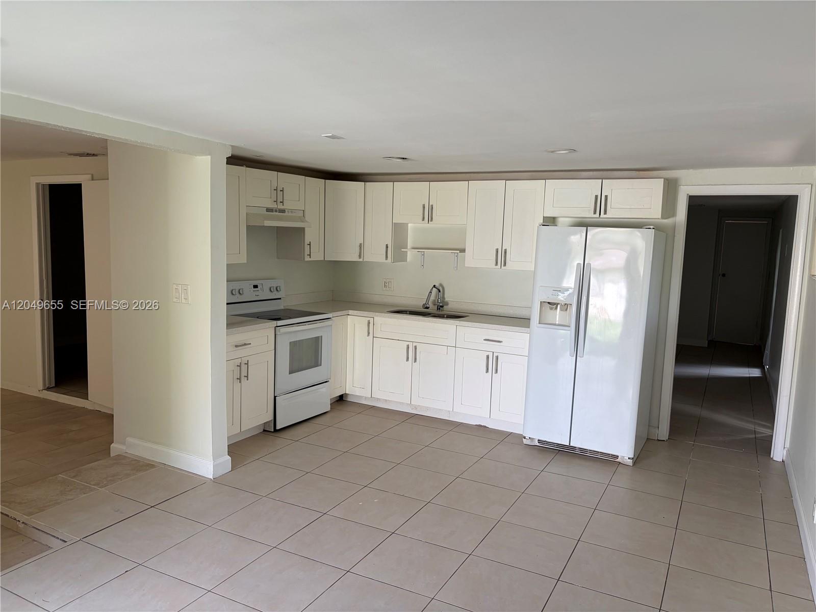 A kitchen features white cabinets, white appliances, and light-colored tile flooring — 5853 Mckinley St # 3, Hollywood FL 33021, HOLLYWOOD, FL