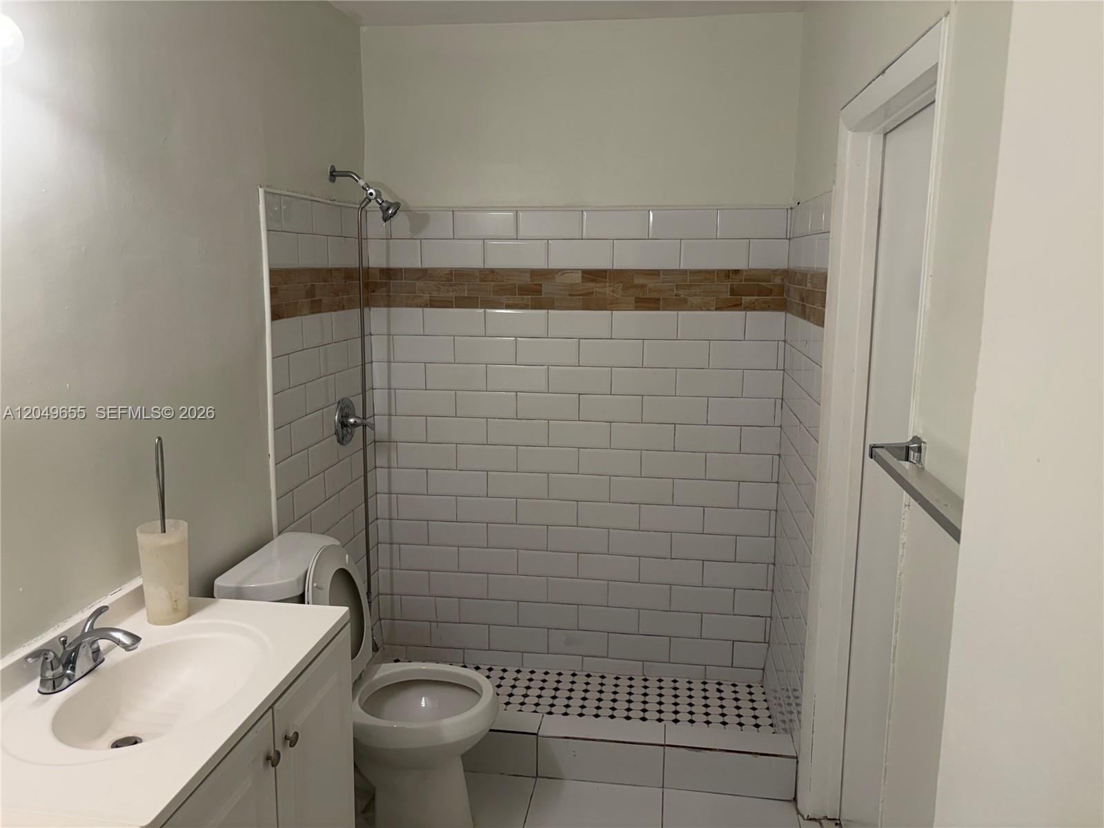 A bathroom features a white vanity, toilet, and a walk-in shower with subway tiles — 5853 Mckinley St # 3, Hollywood FL 33021, HOLLYWOOD, FL