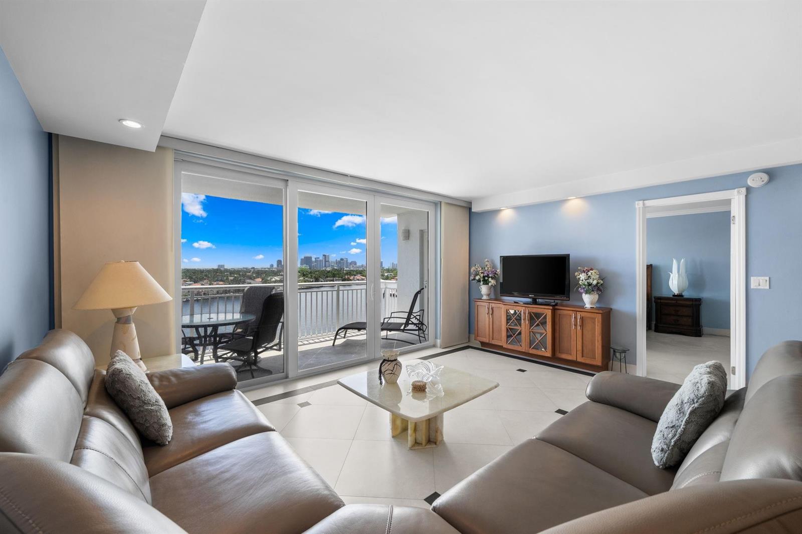 A living room with leather sofas, a coffee table, and a balcony overlooking the city — 511 Bayshore Drive # 904, Fort Lauderdale FL 33304, FORT LAUDERDALE, FL