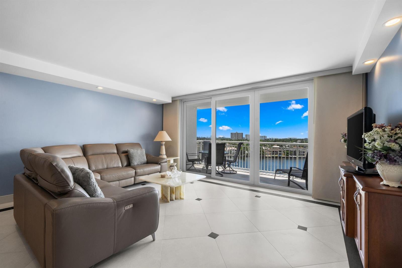 A living room with a leather sectional, tile flooring, and a balcony overlooking water — 511 Bayshore Drive # 904, Fort Lauderdale FL 33304, FORT LAUDERDALE, FL