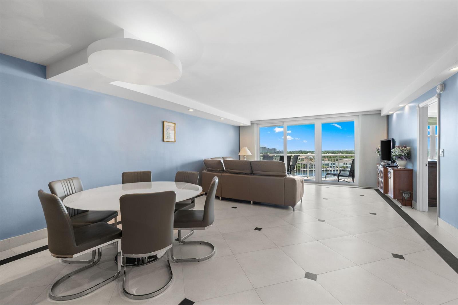 A dining area and living room with light blue walls, tile flooring, and a balcony view — 511 Bayshore Drive # 904, Fort Lauderdale FL 33304, FORT LAUDERDALE, FL