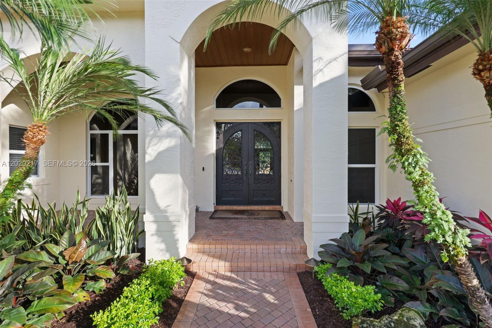 The exterior of a house features a brick walkway leading to an arched double door — 10018 Laurel Rd, Davie FL 33328, DAVIE, FL