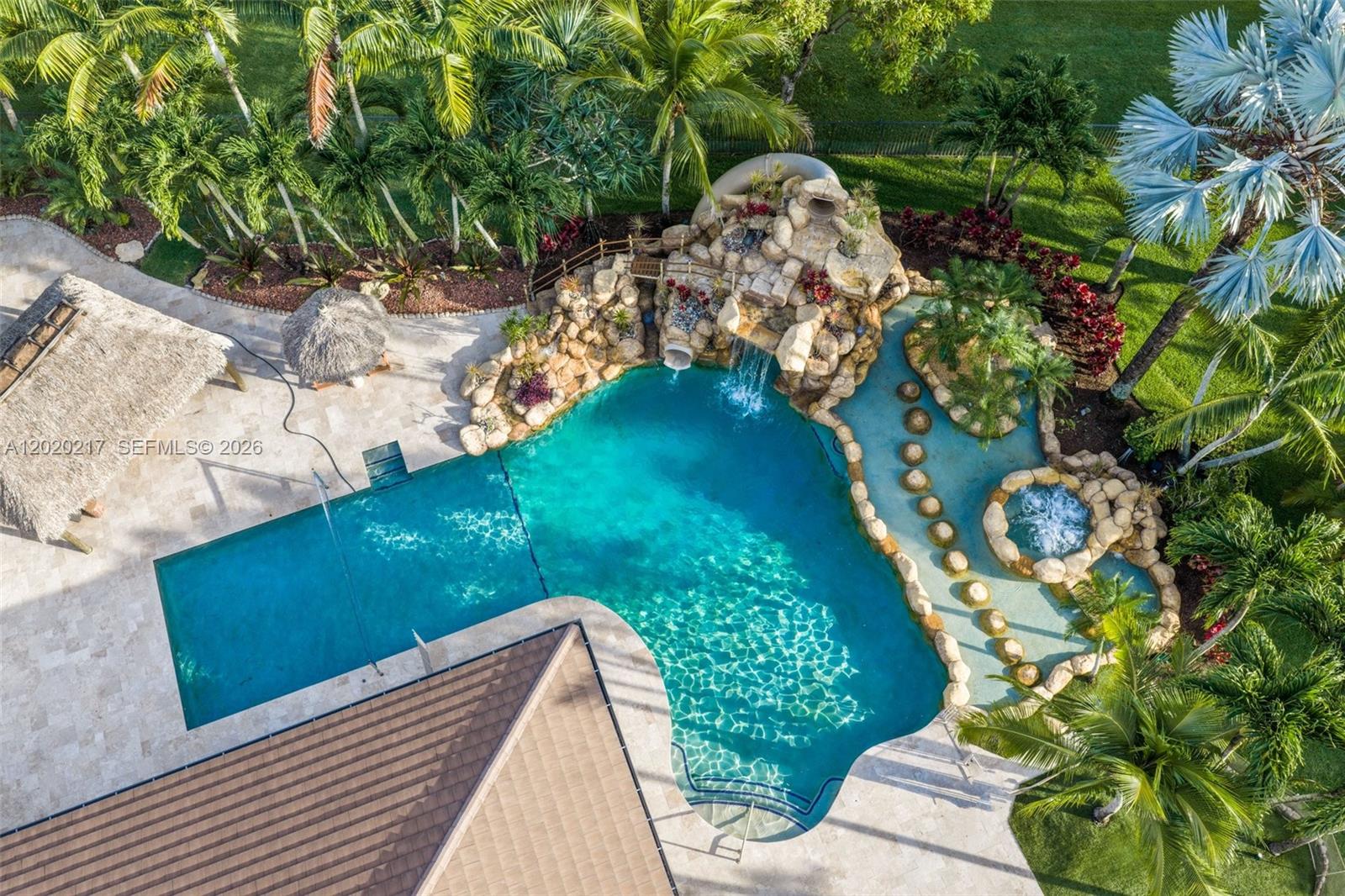 An aerial view shows a swimming pool with a rock waterfall, slide, and attached spa — 10018 Laurel Rd, Davie FL 33328, DAVIE, FL