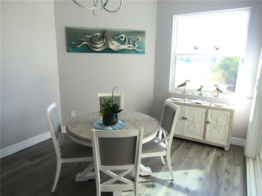 A dining area features a round wooden table, four chairs, and a coastal-themed sideboard — 2064 LITTLE PINE CIRCLE, PUNTA GORDA, FL