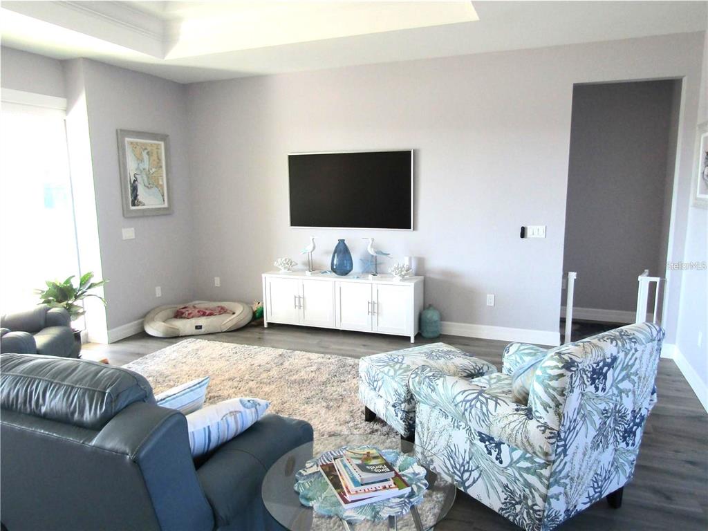 A living room features a wall-mounted television, a white media console, and patterned armchairs — 2064 LITTLE PINE CIRCLE, PUNTA GORDA, FL