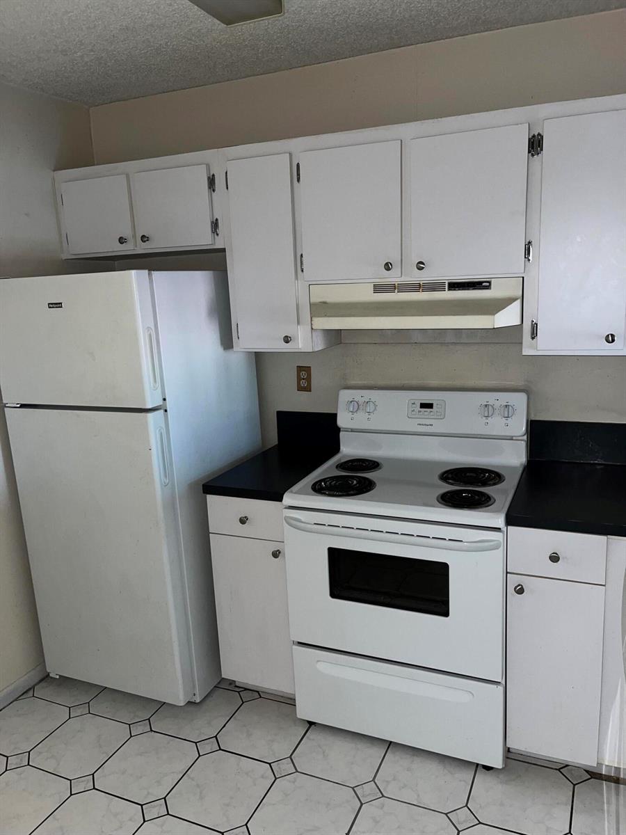 A kitchen features white cabinets, a white refrigerator, a white electric stove, and tiled flooring — 3396 Foxcroft Road # 309, Miramar FL 33025, MIRAMAR, FL