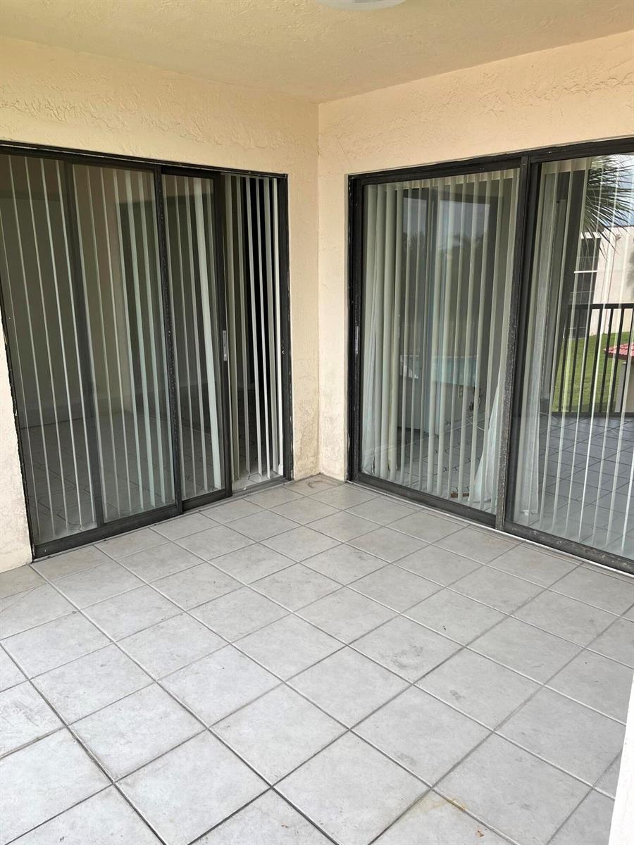 A tiled patio features two sets of sliding glass doors with vertical blinds — 3396 Foxcroft Road # 309, Miramar FL 33025, MIRAMAR, FL