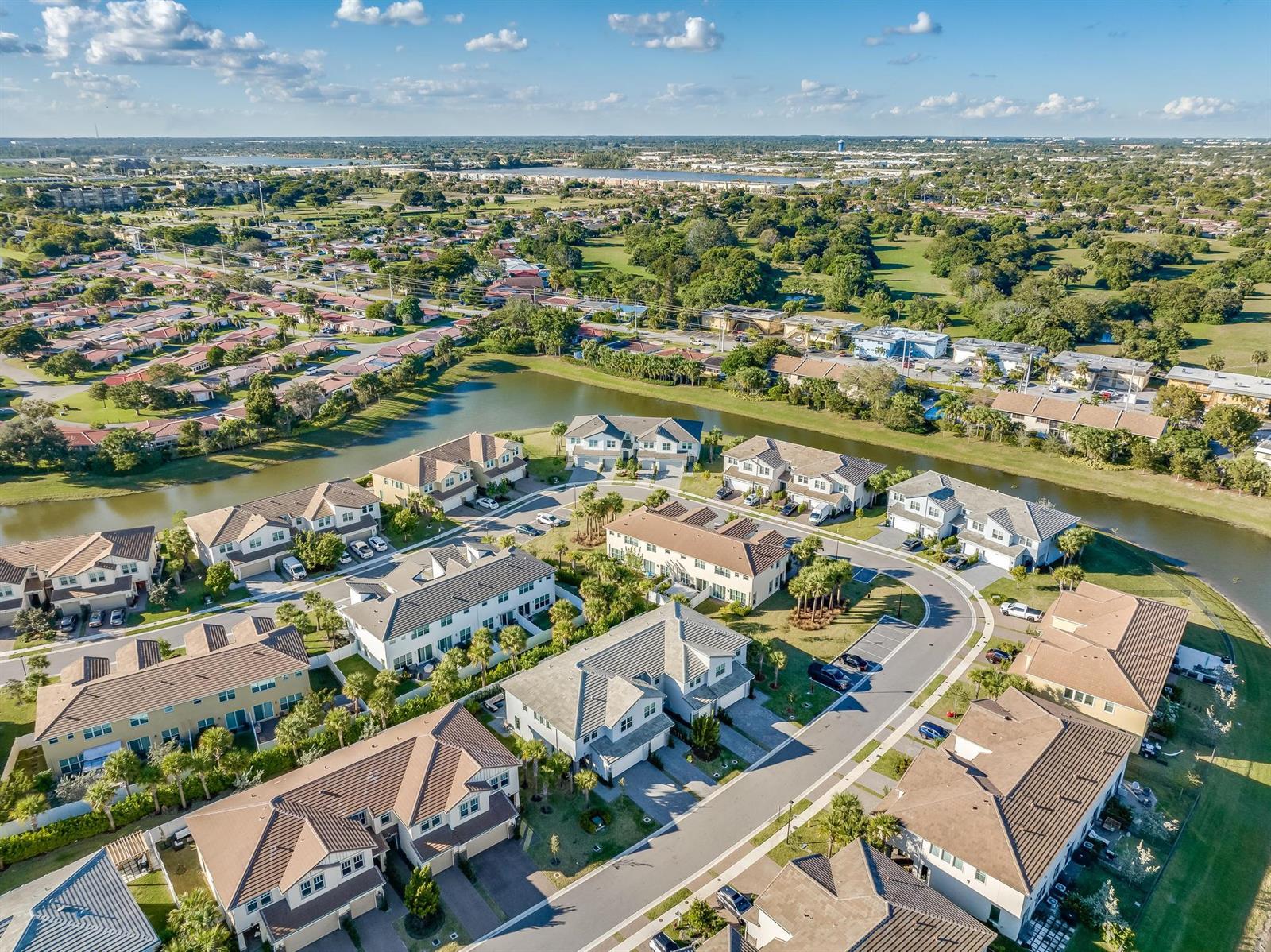 An aerial view shows a suburban neighborhood with multi-story houses, a winding canal, and trees — 4364 Veleiros Avenue, Deerfield Beach FL 33064, DEERFIELD BEACH, FL