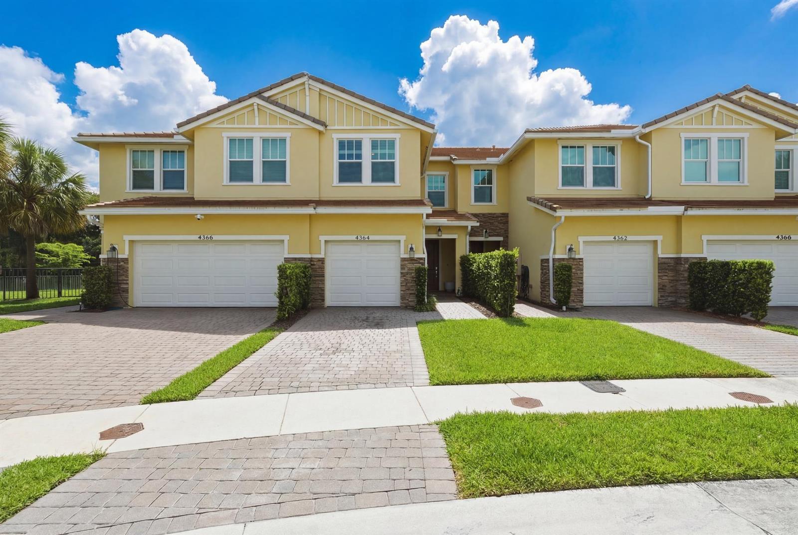 A row of yellow two-story townhouses features paved driveways, white garage doors, and green lawns — 4364 Veleiros Avenue, Deerfield Beach FL 33064, DEERFIELD BEACH, FL