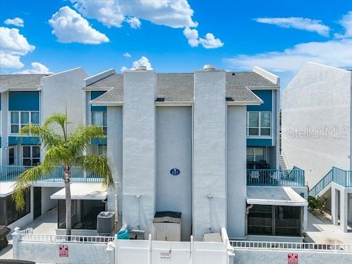 A multi-story townhouse exterior features white stucco walls, blue accents, and a palm tree — 337 REX PLACE UNIT A, MADEIRA BEACH, FL